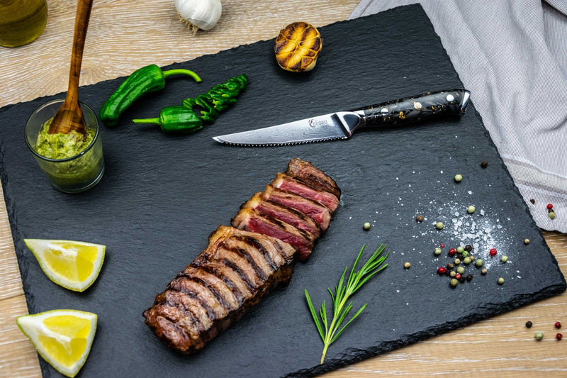 Gold&Ash Steakmesser in einem Servierbrett mit einem Steak, Kräutern und Gewürzen.